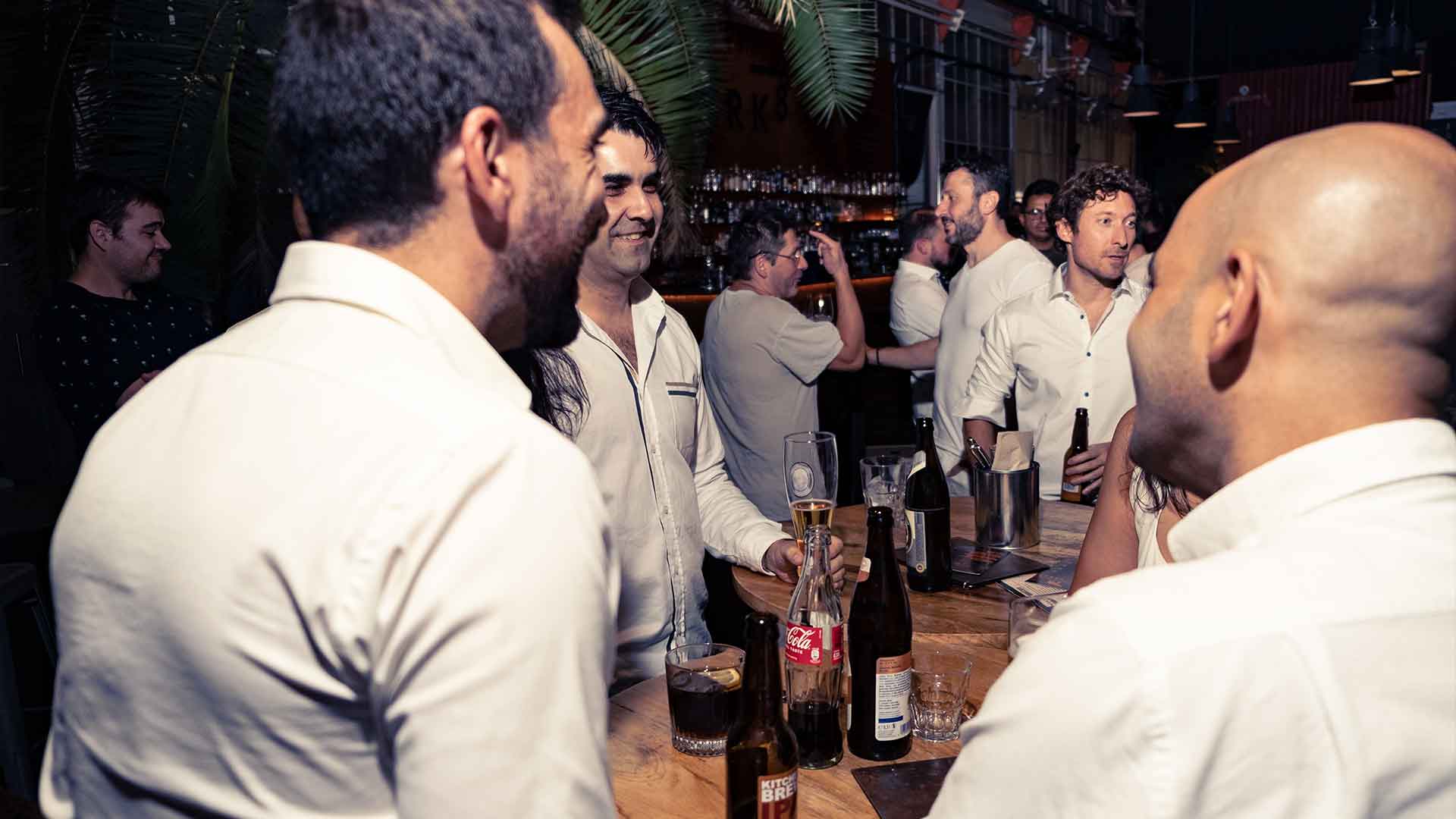 Group of people enjoying a lively conversation at a casual bar gathering.